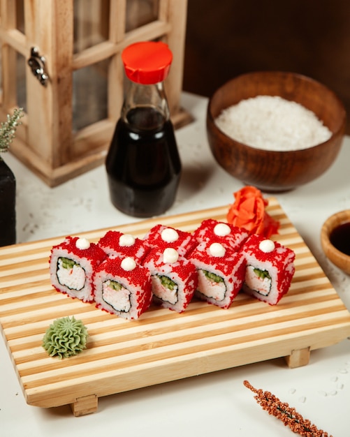 Red sushi rolls on a wooen board.