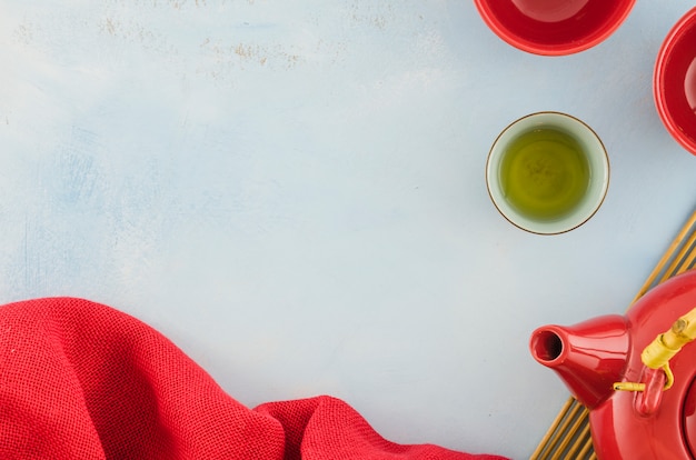 Red textile; tea cups and teapot with copyspace for writing the text on white backdrop