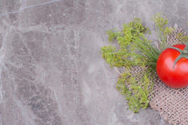 A red tomato with herbs on the marble