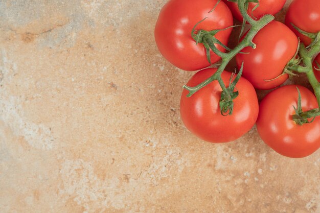 Red tomatoes cherry on a branch on marble surface