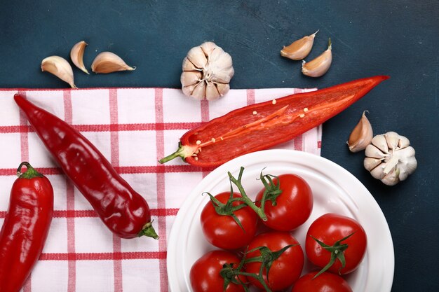 Red tomatoes and chili peppers on a checked towel.