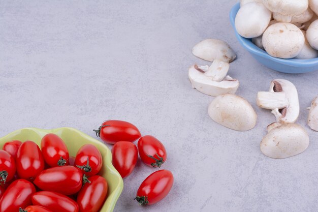 Red tomatoes and mushrooms on grey surface