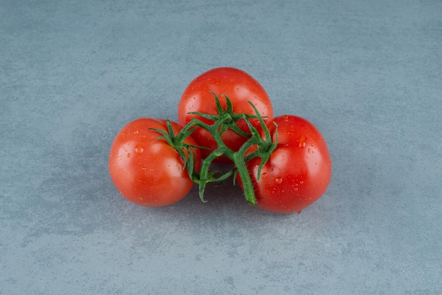 Red tomatoes with water drops on blue.