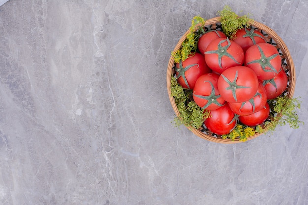 Red tomatoes in a wooden platter on the marble