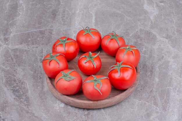 Red tomatoes in a wooden platter on the marble