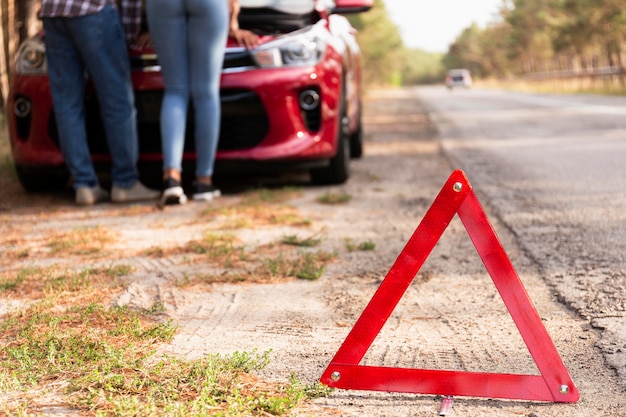 Foto gratuita segno del triangolo rosso sulla strada per problemi con la macchina durante il viaggio