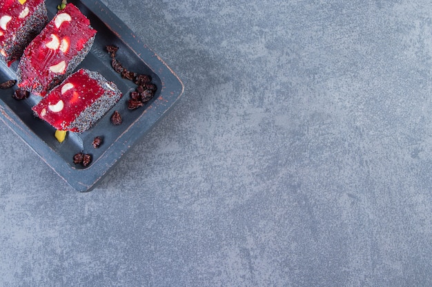 Red Turkish delights in a wooden plate, on the marble background.