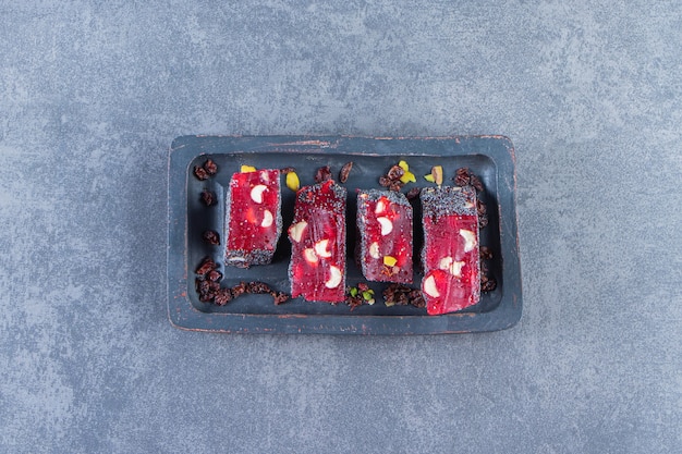 Free photo red turkish delights in a wooden plate, on the marble surface