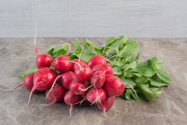 Red turnips and turnip leaves on marble.