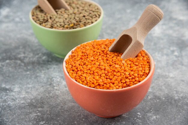 Red uncooked lentils and split peas in colorful bowls.