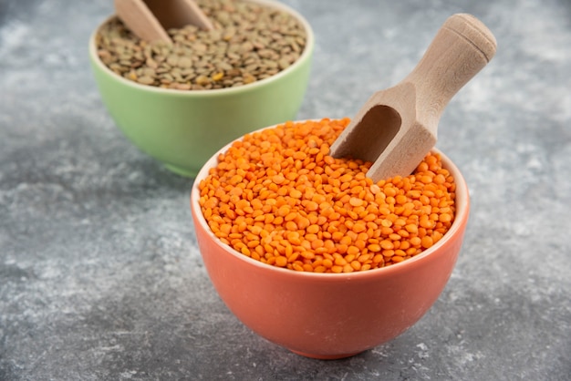 Red uncooked lentils and split peas in colorful bowls.