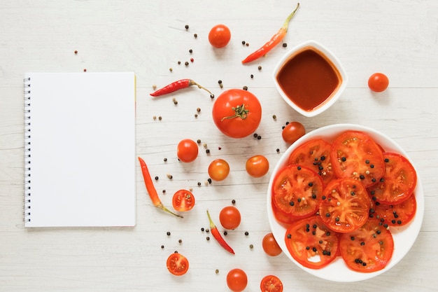 Red veggie food next to empty notebook