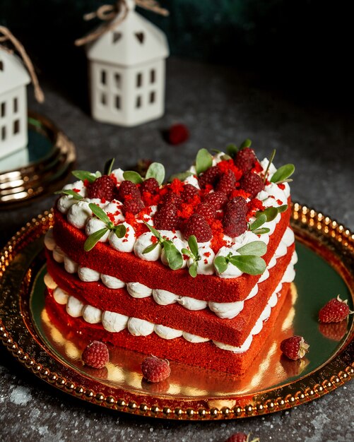 Red velvet cake in heart-shape garnished with raspberries and mint leaves