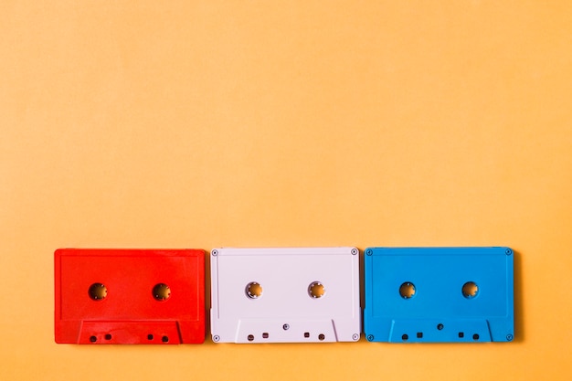 Red; white and blue cassette tapes on colored background