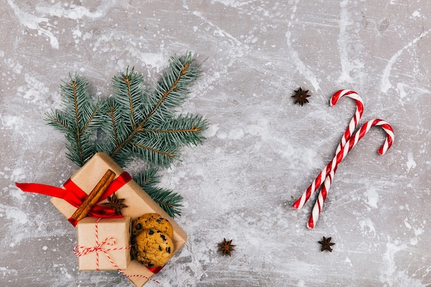 Red white candies, fir branch, present box and cookies on grey floor