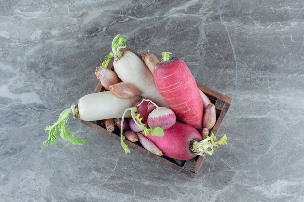 Red and white radishes in the box, on the marble table. 