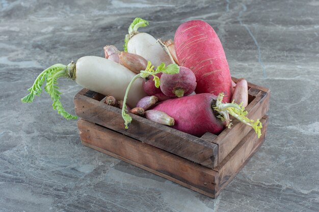 Red and white radishes in the box, on the marble table. 