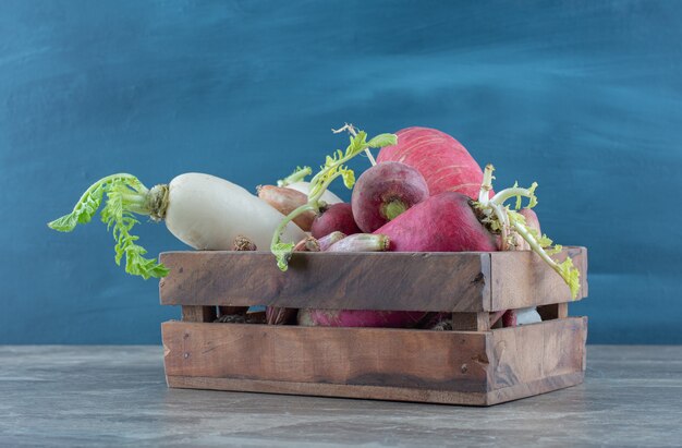 Red and white radishes in the box, on the marble table. 