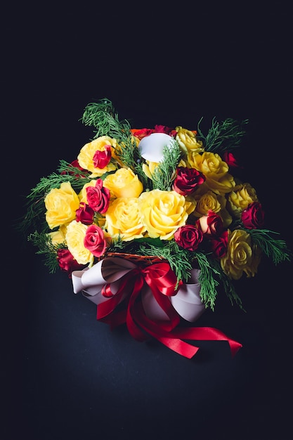 Red and white ribbons twine bouquet of red and yellow roses