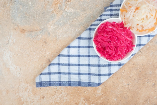 Red and white sauerkraut salads in white bowls with tablecloth