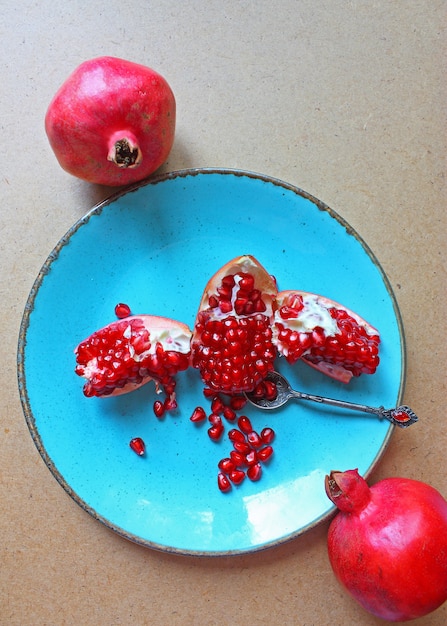 Free photo red whole and cut pomegranates in and outside of the plate