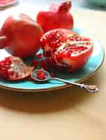 Free photo red whole and cut pomegranates in the plate