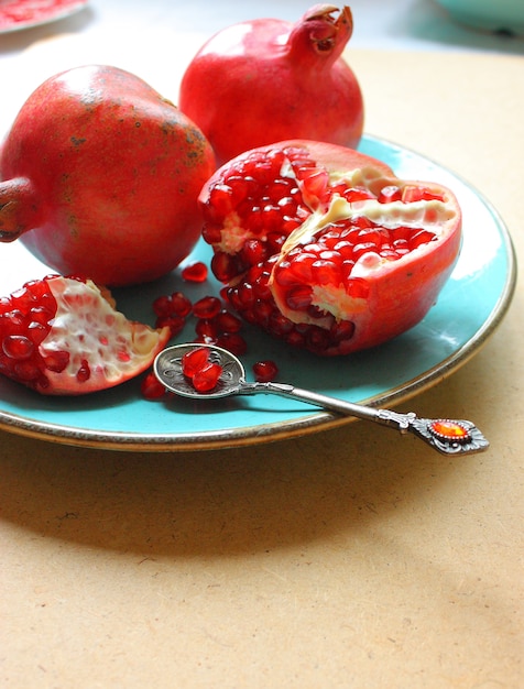 Red whole and cut pomegranates in the plate