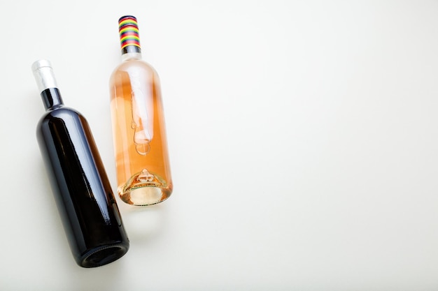 赤ワインボトルとロゼワインボトル。白い背景のコピースペースのミニマルなワイン組成の上面図。ワインブランドのモックアップテンプレート。
