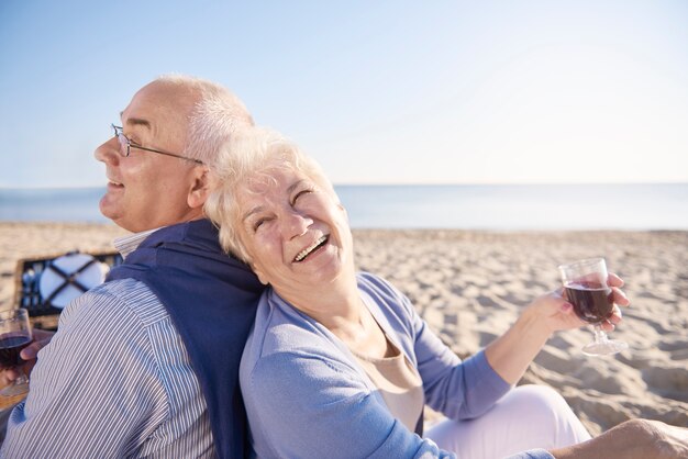 Red wine drunk on the beach. Senior couple in the beach, retirement and summer vacation concept