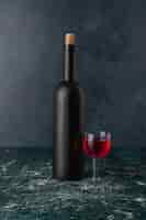 Free photo red wine glass and bottle on marble table.