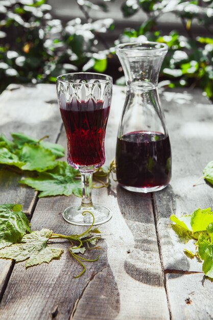 水差しとガラスの木と植物のテーブル、ハイアングルでブドウの葉と赤ワイン。
