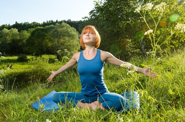 Red woman practicing fitness yoga outdoors