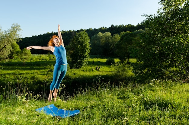 Red woman practicing fitness yoga outdoors
