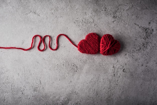 Free photo red yarn heart shaped on the wall background