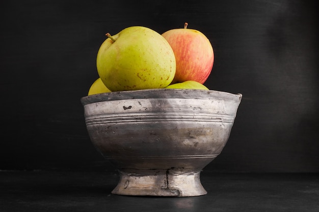 Free photo red and yellow apples in a metallic cup.