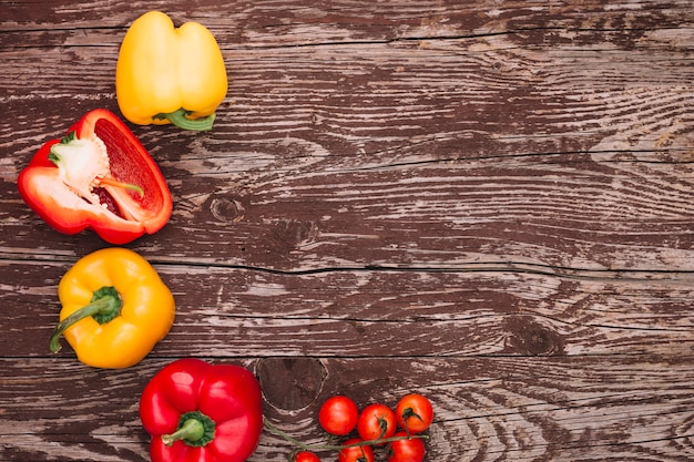 Red and yellow bell peppers and cherry tomatoes over the wooden desk