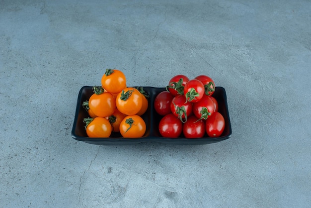 Red and yellow cherry tomatoes in a black platter.