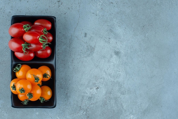 Red and yellow cherry tomatoes in a black platter.