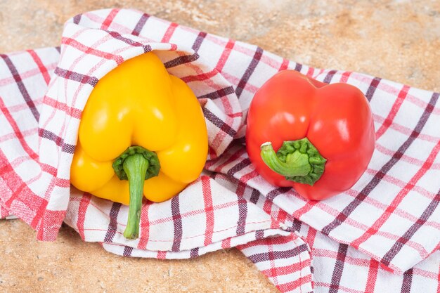 Red and yellow fresh bell peppers on a tablecloth 