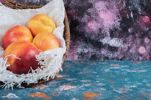 Free photo red and yellow peaches on piece of white burlap.