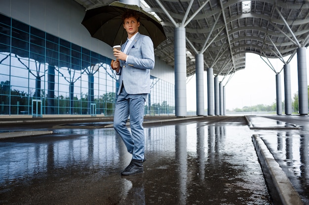 redhaired businessman with umbrella drinking coffee