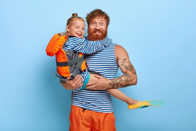 Redhaired daughter and father pose together with swimming equipment
