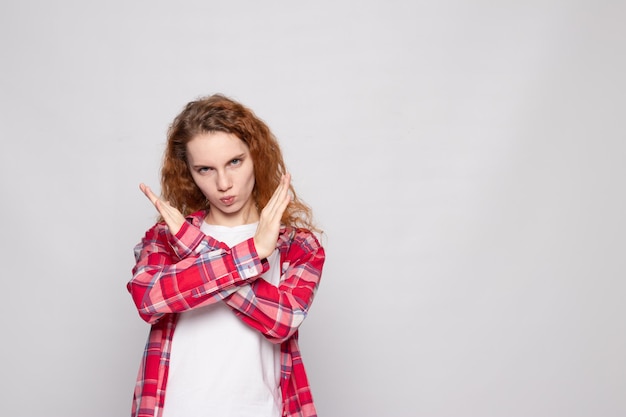 Redhaired young girl in a plaid shirt on a white background with a place for text shows no