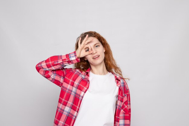 Redhaired young girl in a plaid shirt on a white background with a place for text