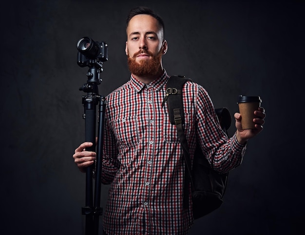 Redhead bearded freelance photographer with tripod and backpack.