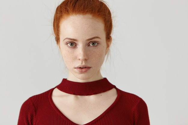 Rossa ragazza caucasica con bel viso con le lentiggini che indossa un abito rosso alla moda con collo tagliato, modellistica isolato