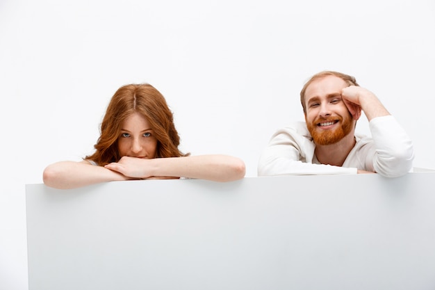 Redhead couple hiding behind table, smiling