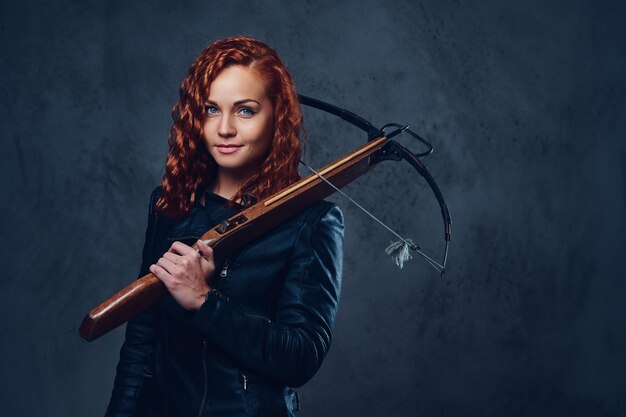 Redhead female dressed in an elegant suit holds crossbow.