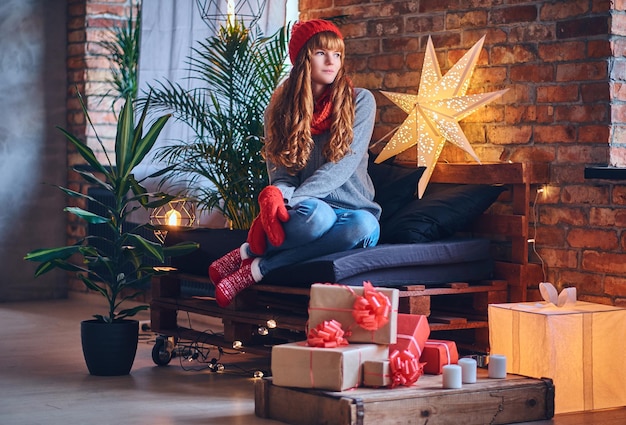 Redhead female drinks a hot coffee in a living room with loft interior.