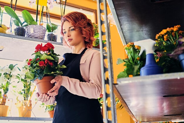 Redhead female holds flower in a pod in a market shop.